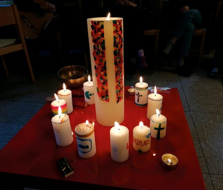 Zentrale Kerze umgeben von mehreren kleineren Kerzen auf einem Tisch.