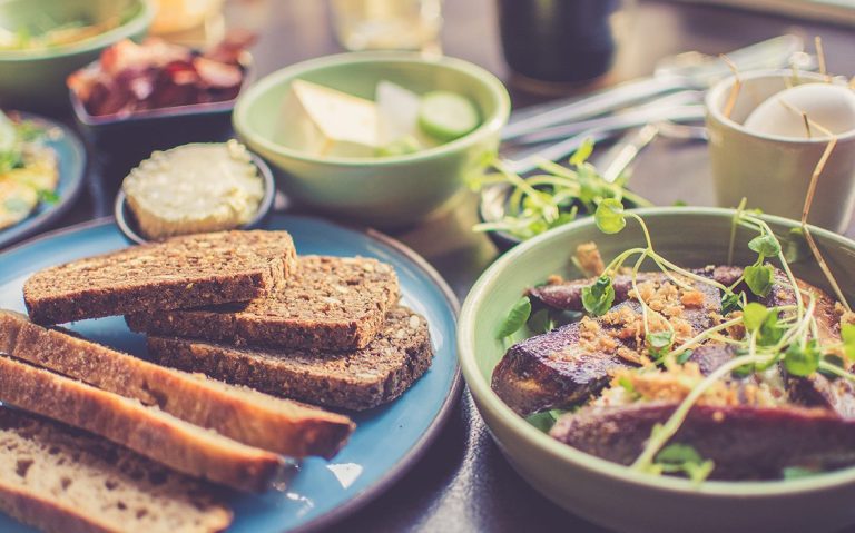 Verschiedene Gerichte mit Brot, Gemüse und Fleisch auf einem Tisch angerichtet.