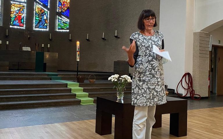 Frau steht in der Epiphaninekirche und spricht mit Notizen in der Hand.