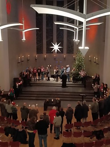 Festliche Veranstaltung in einer Kirche mit einer Vielzahl von Menschen und weihnachtlicher Dekoration.
