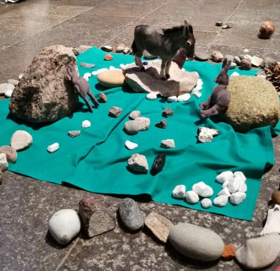 Ein grünes Tuch mit Steinen und zwei Pferdefiguren in einer kreisförmigen Anordnung.