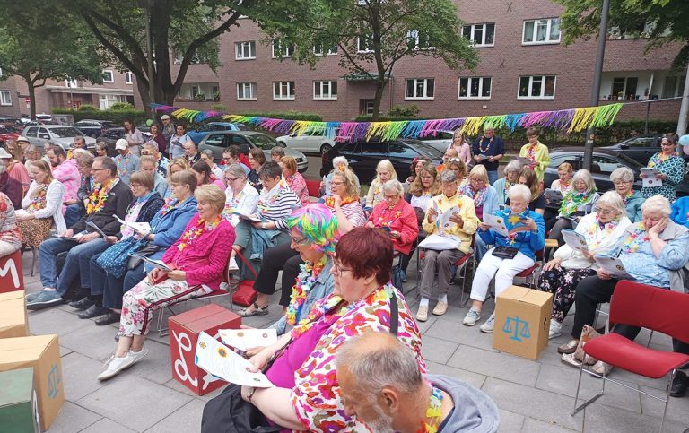 Zwei lächelnde Frauen, Jette Wrobel und Heike Schoof, stehen vor blühenden Rosen vor der Epiphanienkirche.