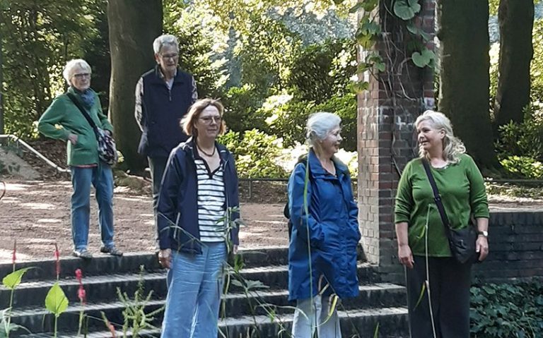 Fünf Personen stehen im Stadtpark, umgeben von Pflanzen und Bäumen.