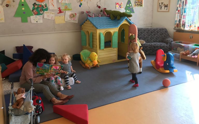 Kinder spielen in der Kinderetage mit Spielzeug und einer kleinen Spielhütte.