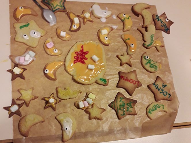 Epiphaniengemeinde Hamburg – Jugendkeller Bunte, verzierte Plätzchen in verschiedenen Formen auf braunem Papier.