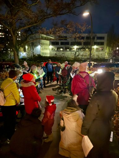 Gruppierung von Menschen in Winterkleidung bei einer Abendveranstaltung im Freien.
