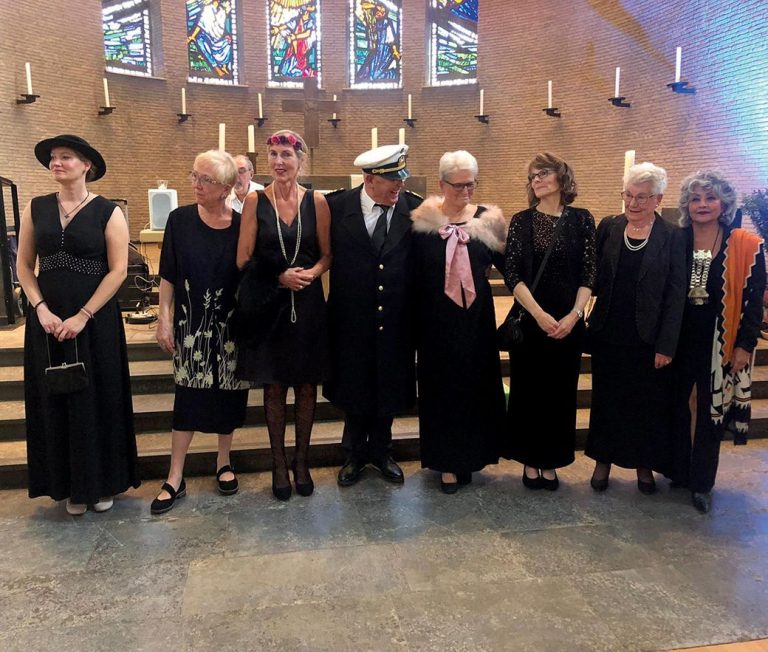 Eine Gruppe von neun Personen in eleganter Kleidung steht in der Epiphaninekirche.