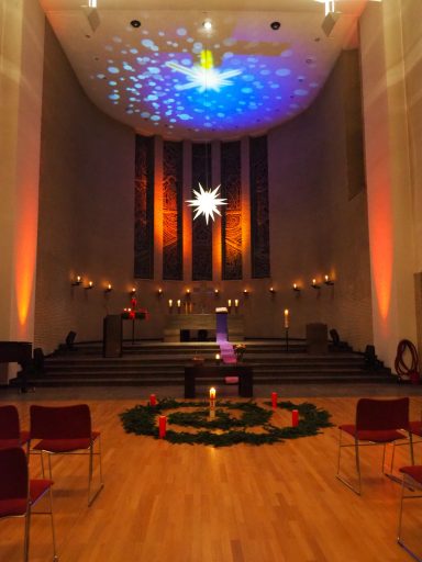 Festlich dekorierte Kirche mit einen leuchtenden Stern und Kerzen in einem runden Arrangement.